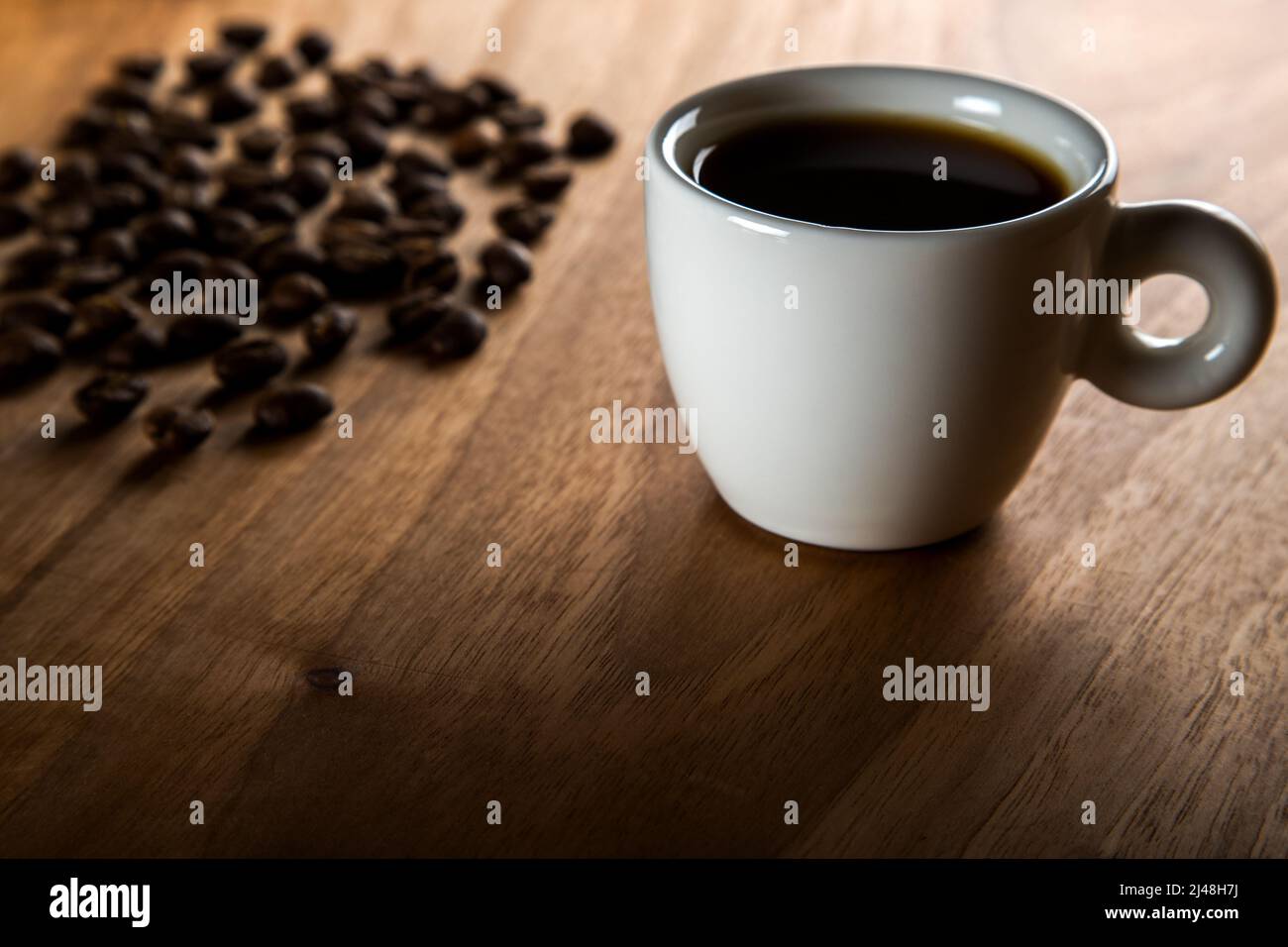 Weiße Tasse Kaffee mit Kaffeebohnen auf Holzhintergrund Stockfoto