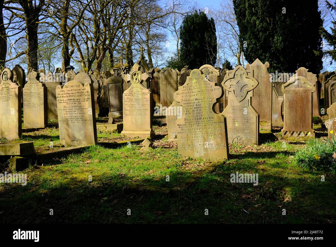 Grabsteine im Sonnenlicht, Haworth Parsonage Friedhof in Spring, West Yorkshire Stockfoto