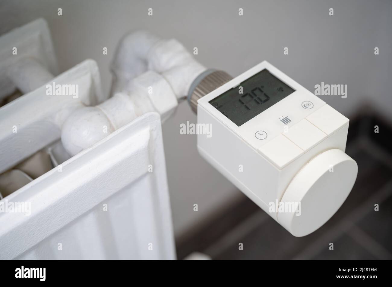 Modernes intelligentes Heizventil mit Thermostat, das an einen alten Heizkörper für Warmwasserbereitung nachgerüstet wurde, um die Raumtemperatur zu regeln Stockfoto