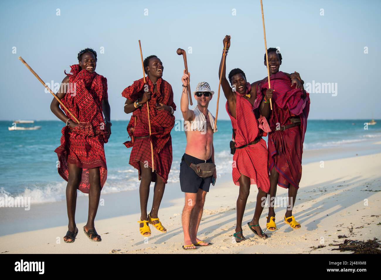 Sansibar, Tansania - April 22,2022: Masai-Krieger in traditioneller Kleidung am Sandstrand der Insel Sansibar. Stockfoto