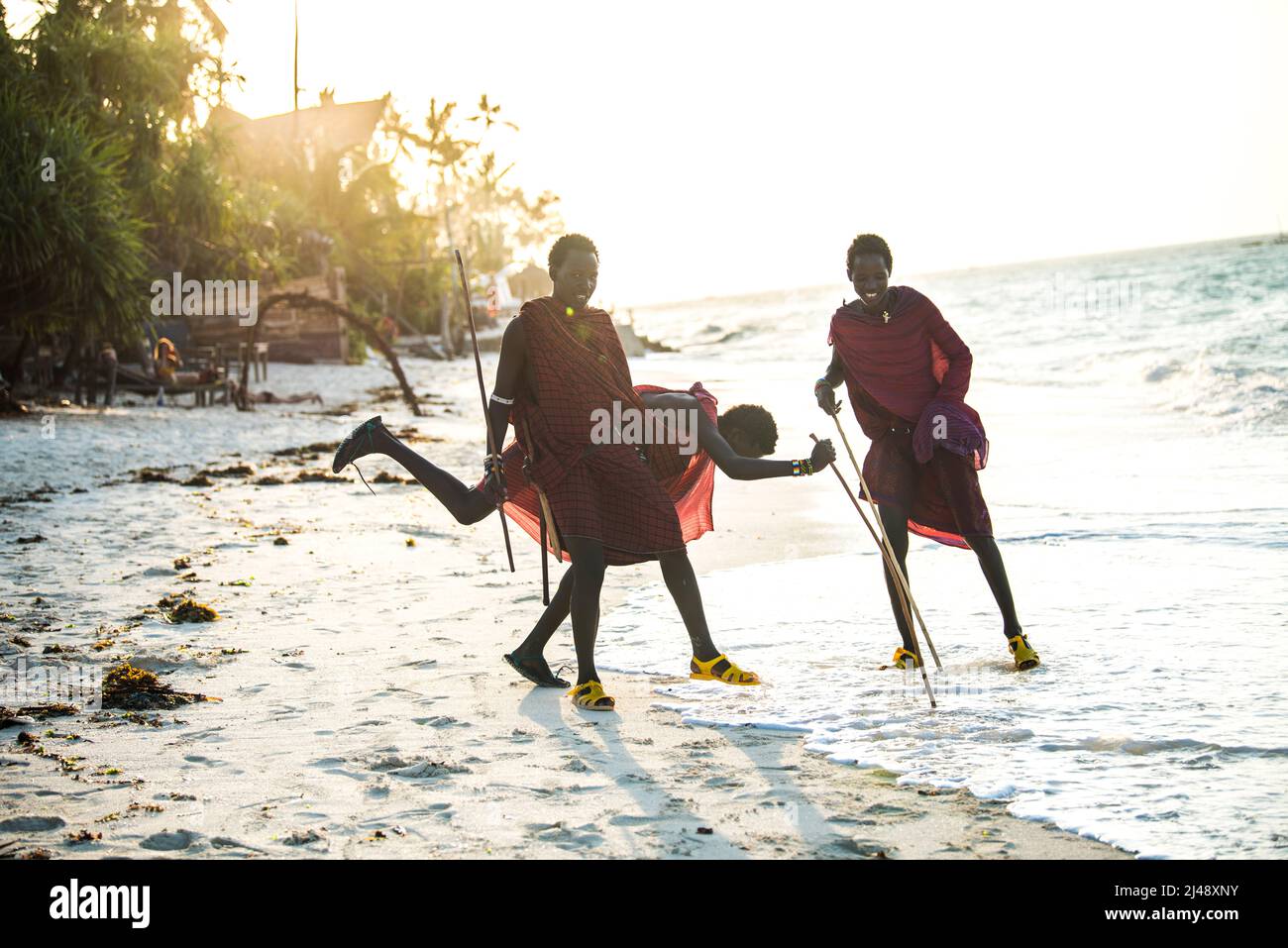 Sansibar, Tansania - April 22,2022: Masai-Krieger in traditioneller Kleidung am Sandstrand der Insel Sansibar. Stockfoto