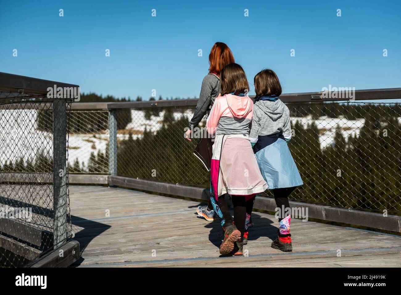 Aktives Familienwandern, Wandern in der Natur auf Holzkegeln im Winter. Familie mit Kindern wandern auf Holzbalkon Baumkronen o Stockfoto