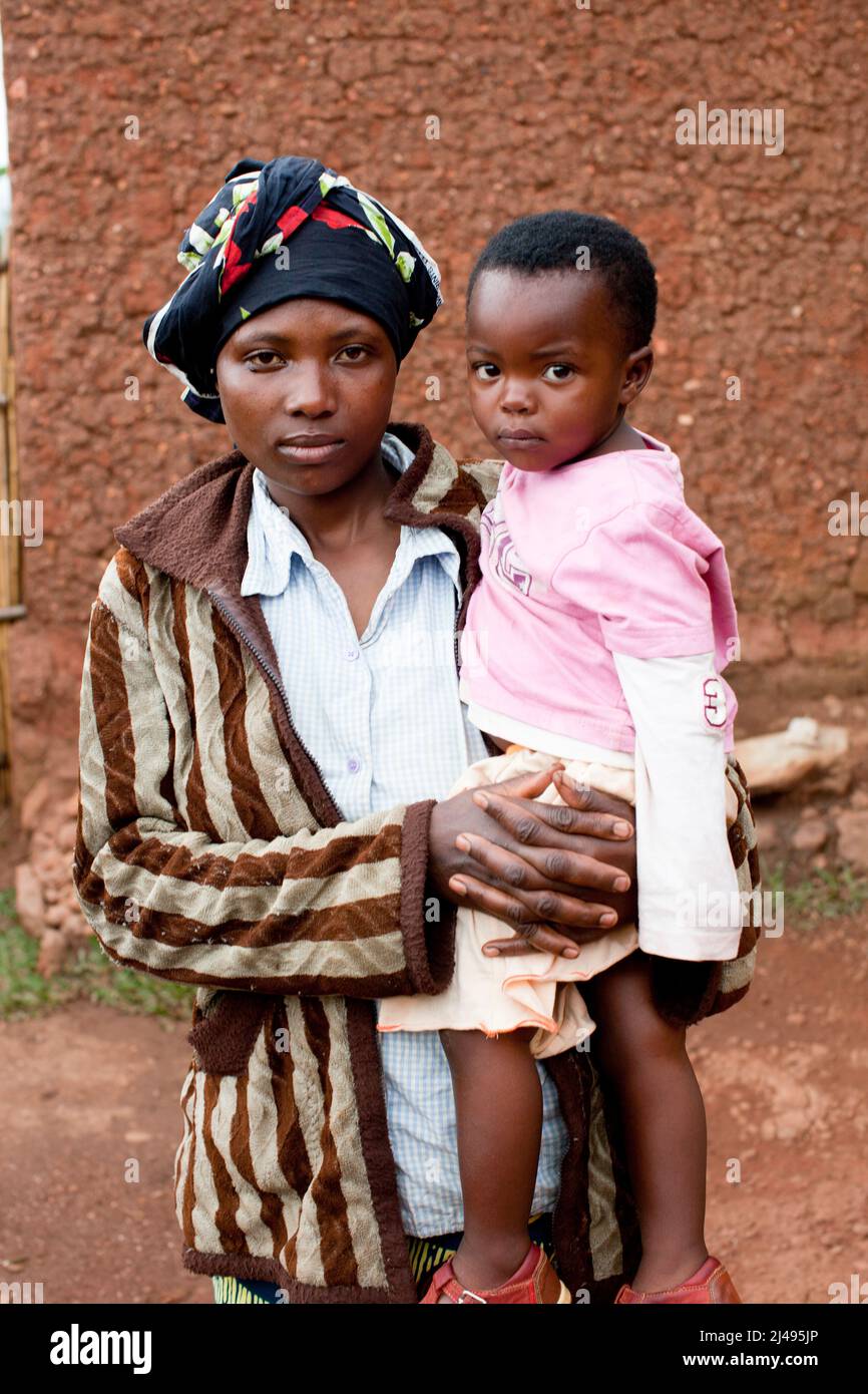 Thacien Kalinda, 24, mit seiner Ehefrau Chantal Nyiraneza, 24, und dem Baby Gisele Uwase vor seinem Familienhaus. Seine Familie floh 1994 mit 7 Jahren in den Kongo. Er wurde von seinen Eltern und sieben Brüdern und Schwestern getrennt, die er seitdem nie mehr gesehen hat. Er war bei einer Tante, die ihn 1996 nach Hause brachte. Sie starb im Alter von 18 Jahren im Grundschule 6 und er brach die Schule ab, weil er sich die Schulgebühren nicht leisten konnte. Er lebte als Straßenjunge, bis er sich an dem Programm beteiligte. Als Ergebnis des Projekts konnte er das Land, das er von seinem Vater geerbt hat, bewirtschaften und 300.000 Fra zurückzahlen Stockfoto
