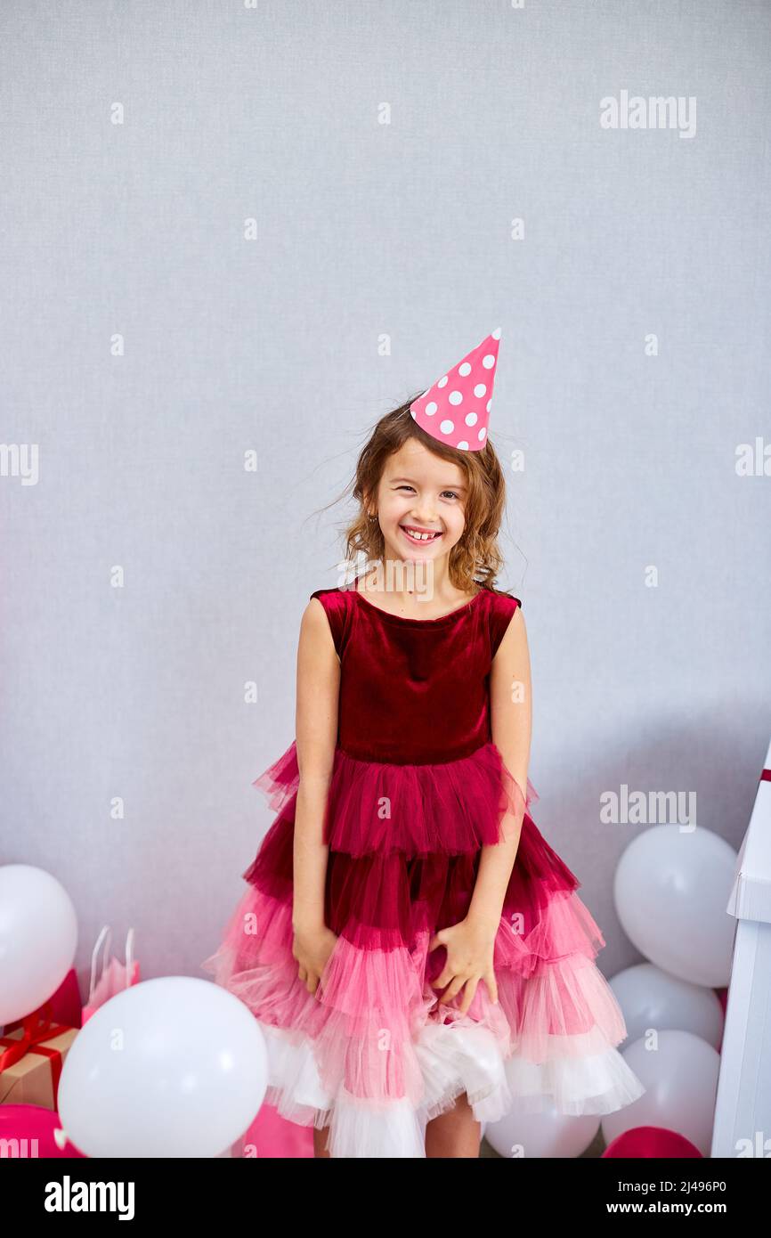 Nette, fröhliche kleine Mädchen in rosa Kleid und Hut spielen mit  Luftballons zu Hause Geburtstagsfeier Streamer, Alles Gute zum Geburtstag.  Feiern Stockfotografie - Alamy