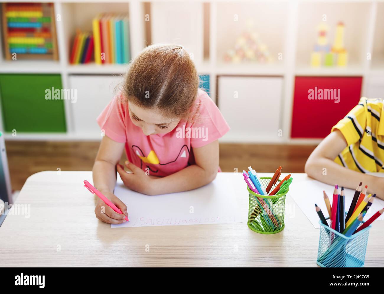 Schulmädchen im Klassenzimmer sitzen an den Tischen und schreiben eine Lektion. Stockfoto