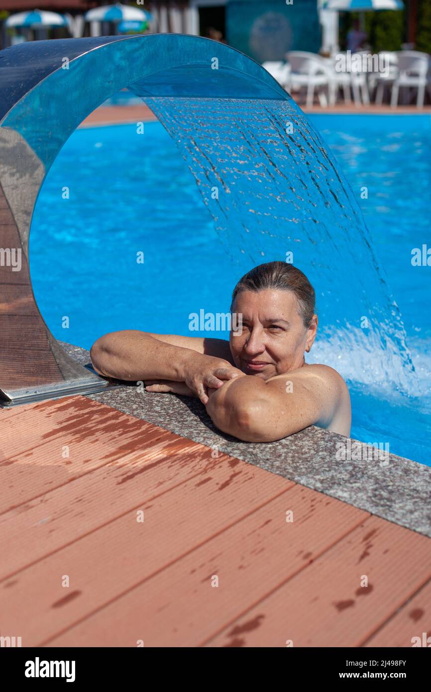 Geothermisches Spa-Zentrum. Wunderschöne Frau entspannt sich unter dem Wasserfall mit Hydromassage im tropischen Resort auf dem Meer Stockfoto