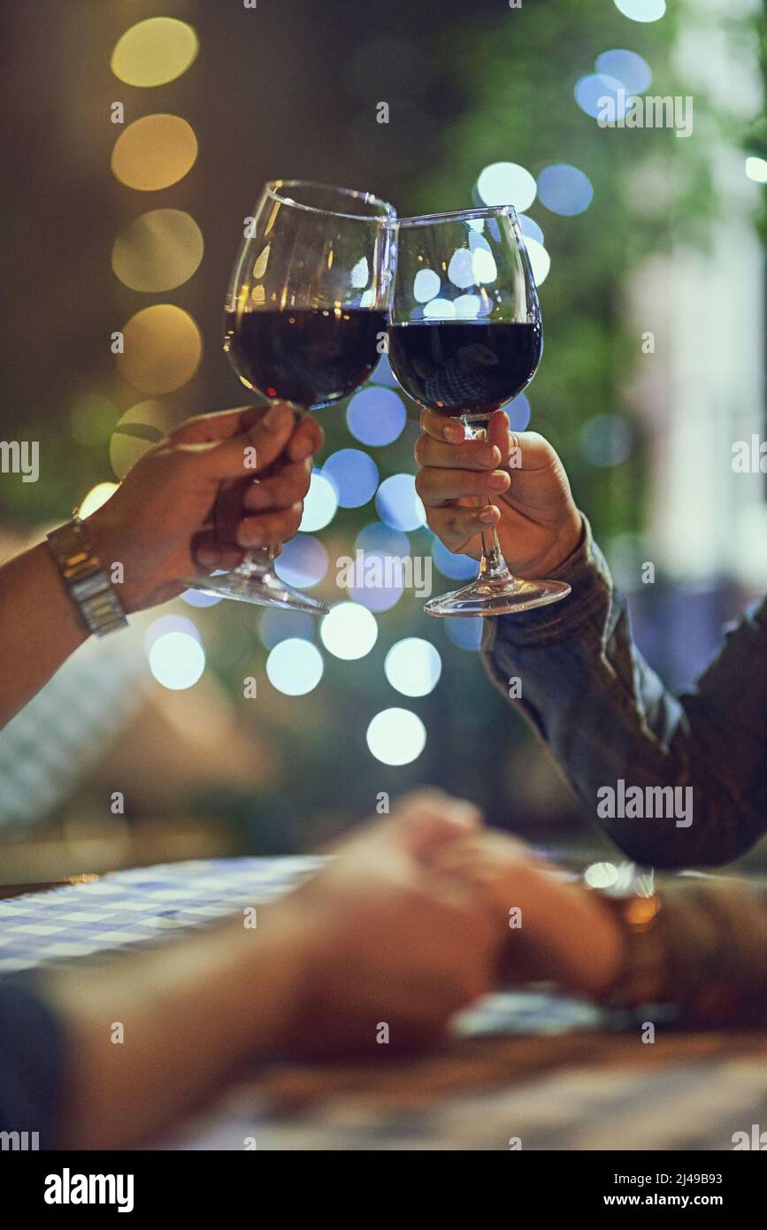 Heres zu unserer ewigen Liebe. Eine kurze Aufnahme eines Paares, das bei einem romantischen Date mit der Brille klirst. Stockfoto