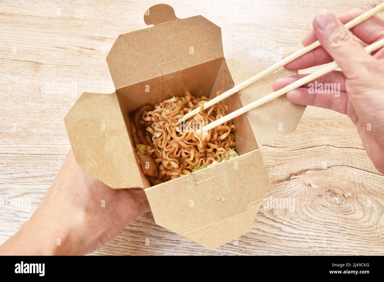 Gebratene japanische Yakisoba-Nudeln schneiden Schweinespeck und Kohl in einer Schachtel und essen mit Holzstäbchen Stockfoto