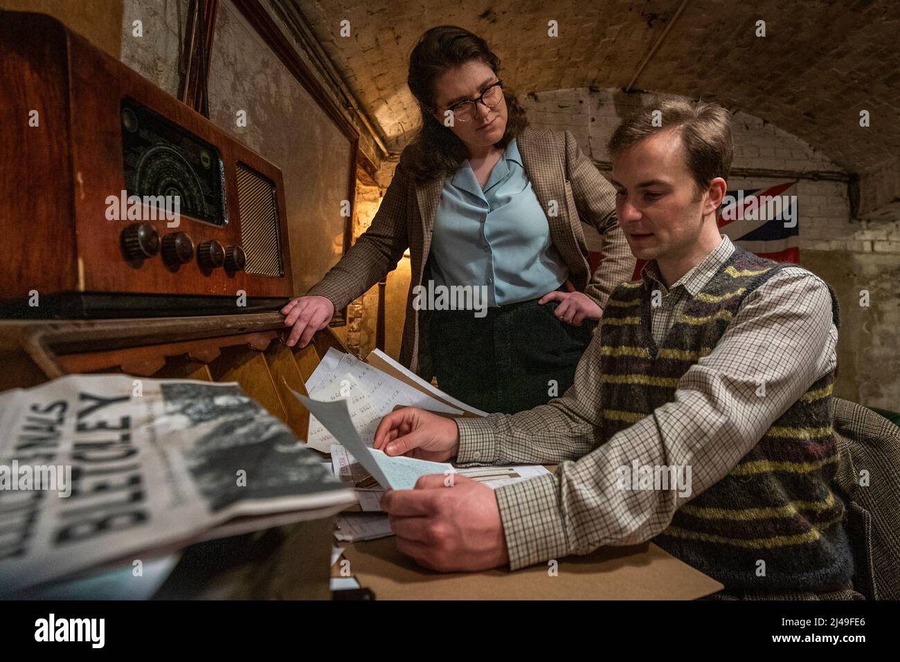 London, Großbritannien. 13. April 2022. (L) Amelia Stephenson (Joan Clarke) und Timothy Styles (Alan Turing) treten bei einer Fotoserie für „illegale Signale Bletchley“ auf, einer Koproduktion zwischen Parabolic Theatre und Mechanical Thought, in der das Publikum mit berühmten Persönlichkeiten aus dem Government Code des Bletchley Parks und der Cipher School zusammenarbeitet, um Enigma zu knacken. Die Show findet vom 2. Bis 28. Mai 2022 in der KRYPTA der Peterskirche in Bethnal Green statt. Kredit: Stephen Chung / Alamy Live Nachrichten Stockfoto