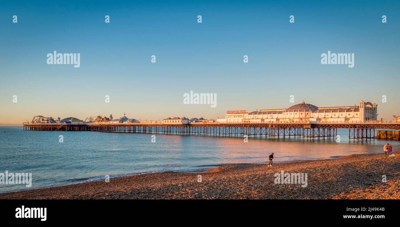 14. Januar 2022: Brighton, East Sussex, Großbritannien - Sonnenaufgang am Brighton Palace Pier, mit Menschen am Strand. Stockfoto