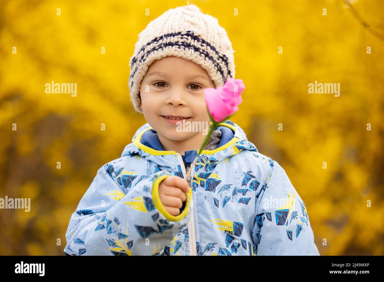 Wunderschönes Kind, Kleinkind, mit rosa Papierblume, handgefertigt für die Mutter zum Muttertag Stockfoto
