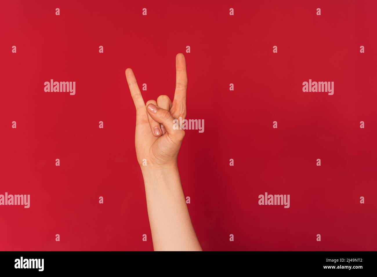 Frauenhand zeigt Rock and Roll-Symbol vor rotem Hintergrund Stockfoto