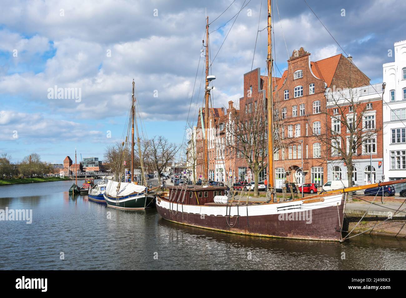 Lübeck, 11. April 2022: Historische Holzsegelschiffe im Museumshafen an der Trave am Kai der Altstadt von Lübeck mit St. Stockfoto