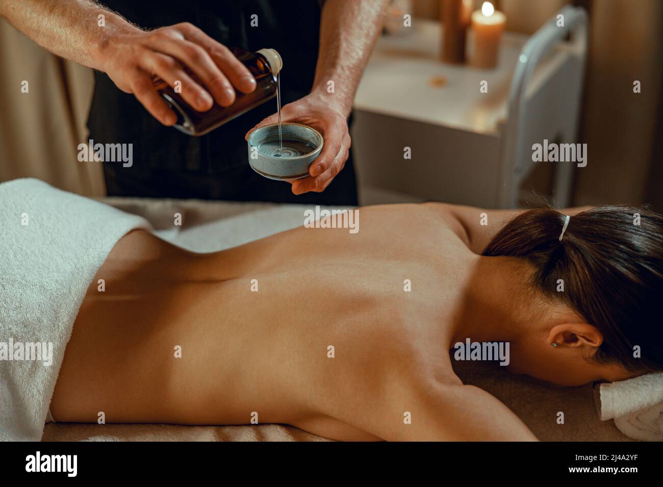 Masseur Mann Therapeut Gießen warme Kräuter infundiert Öl zurück Massage zu machen Stockfoto