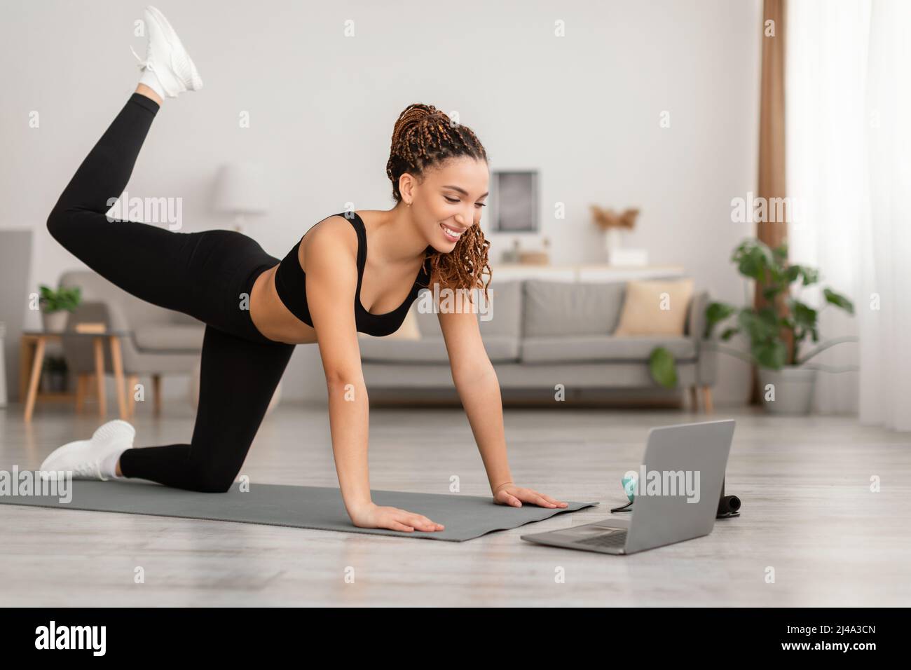 Black Lady In Der Nähe Von Laptop Tun Hüften Übung Zu Hause Stockfoto