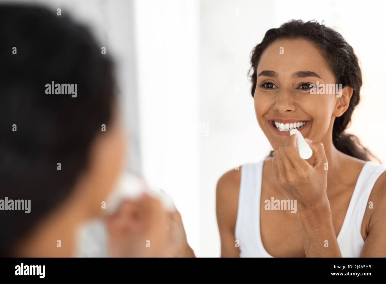 Schöne Junge Dame, Die Den Spiegel Anschaut Und Feuchtigkeitsspendenden Lippenbalsam Anwendet Stockfoto