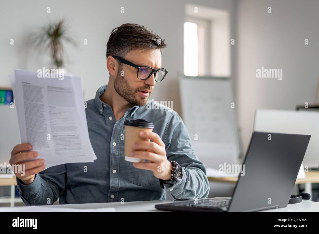 Reifer Mann CEO des IT-Unternehmens sitzt am Arbeitsplatz vor dem Laptop, lesen Bericht und Blick auf den Computer-Bildschirm Stockfoto