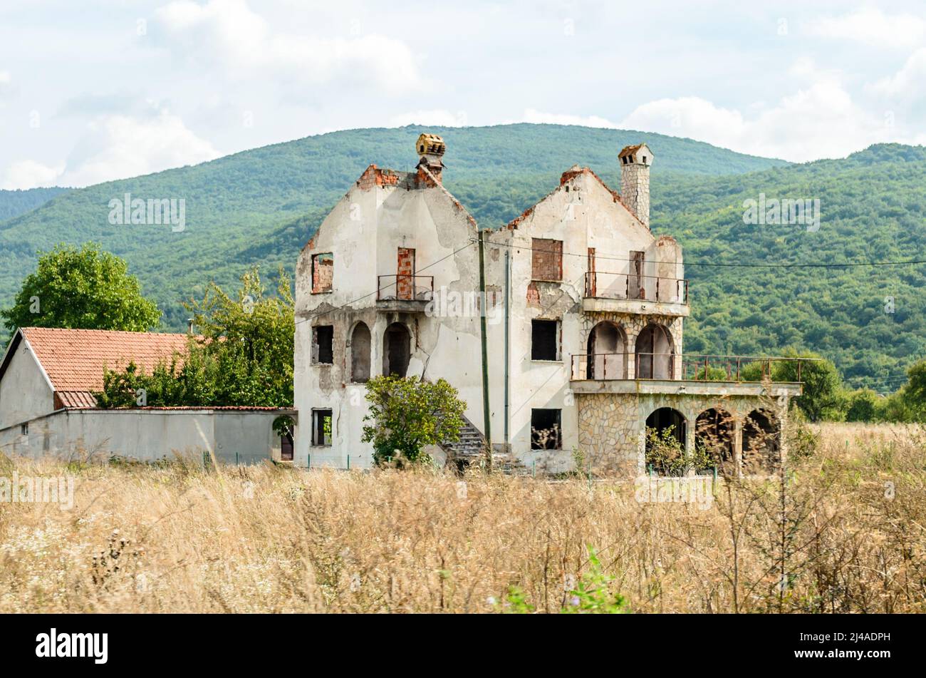 Altes abgerissene und zerstörte Gebäude auf dem Land von Kroatien. Eingestürztes Dach und Fassade voller Bullet-Löcher aus der Zeit des Kroatischen Krieges. Stockfoto