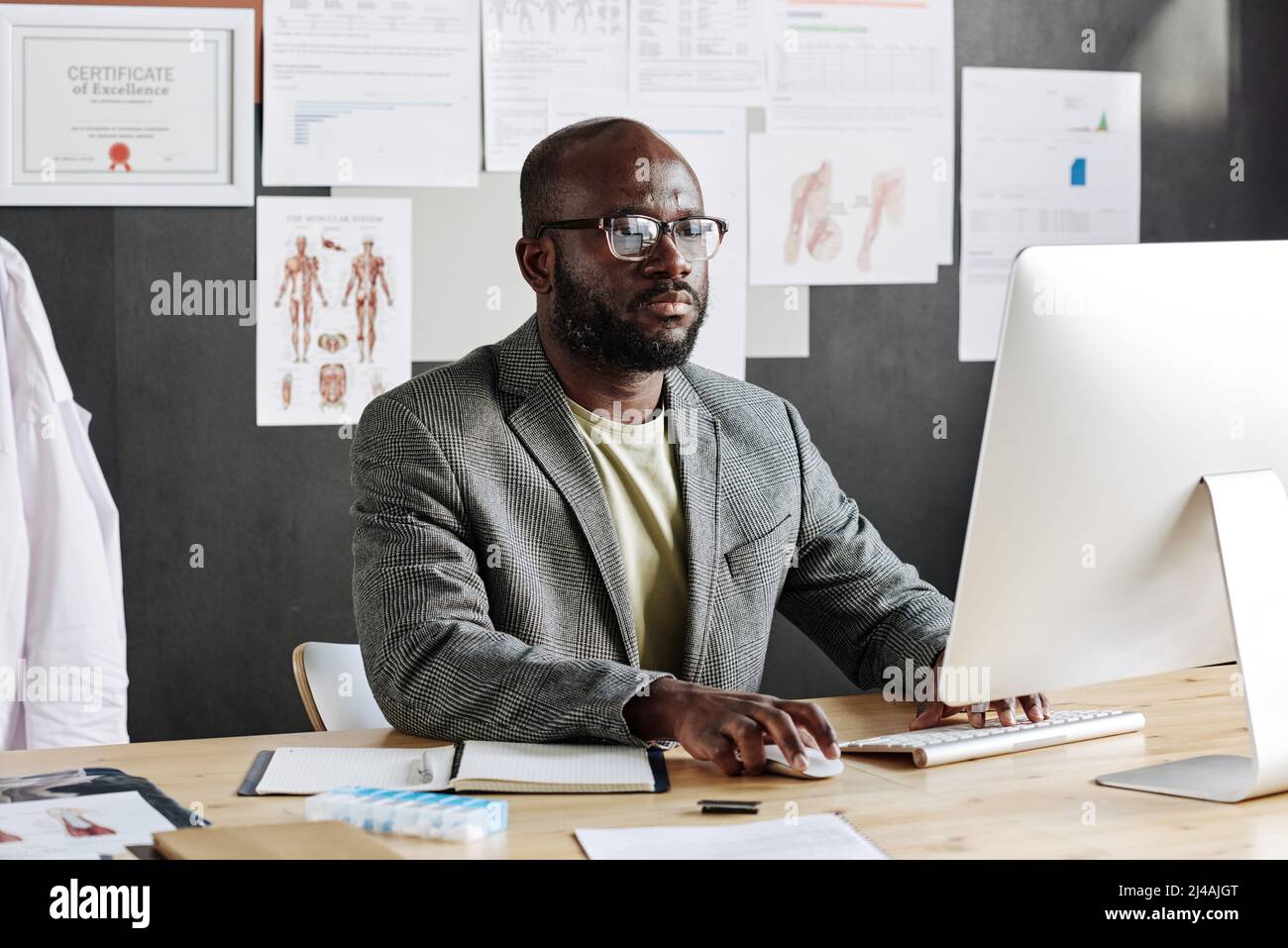 Seriöser afrikanischer Geschäftsmann, der an seinem Arbeitsplatz im Büro am Computer arbeitet Stockfoto