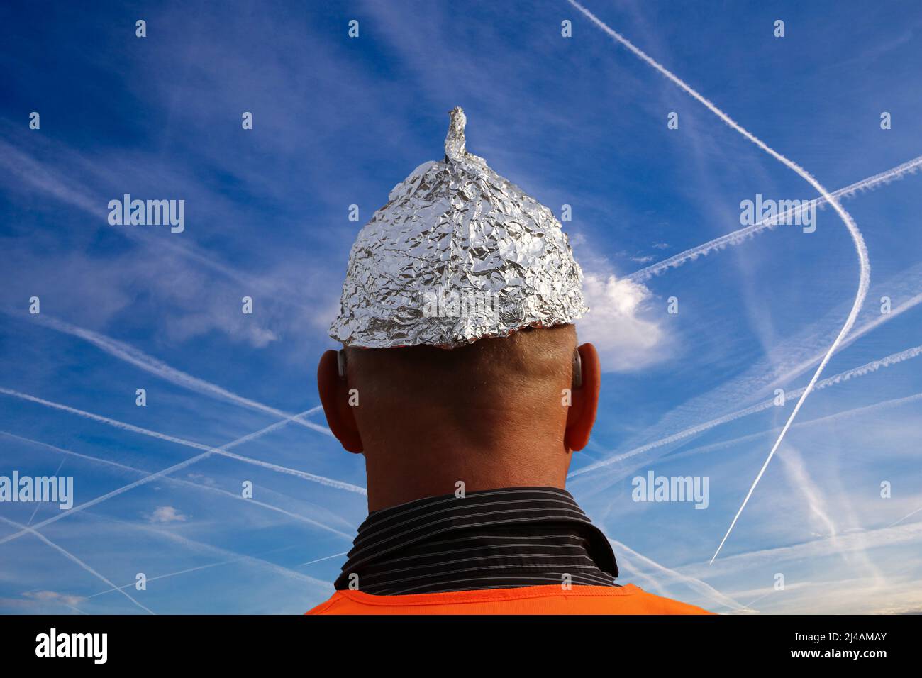 Symbolbild des Verschwörungstheoretikers: Aluhut-Trägerin blickt auf einen Himmel voller Chemtrails (komponieren) Stockfoto