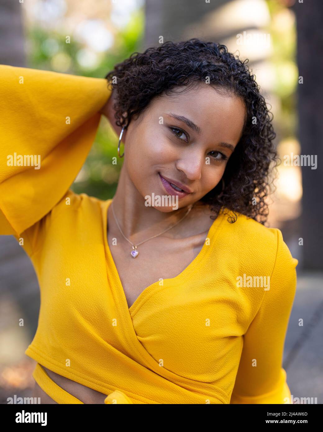 Nahaufnahmen von Porträts einer jungen schwarzen Frau im strahlenden Sonnenlicht, die in einem Garten sitzt Stockfoto