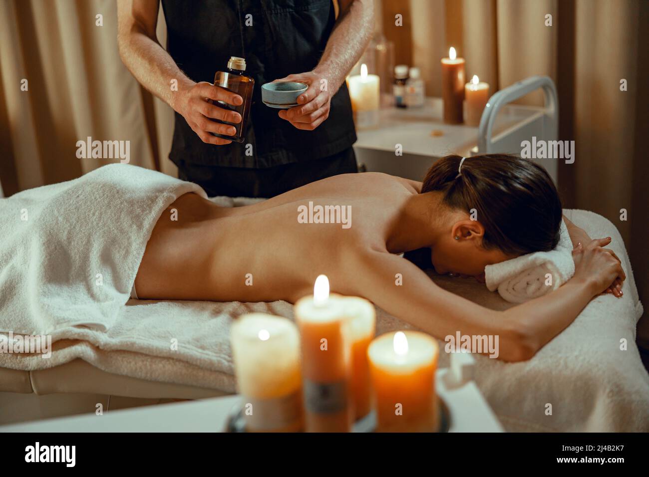 Alternativer Schönheitssalon Therapeut bereitet warmes Kraut infundiert Öl für weibliche Rückenmassage Stockfoto