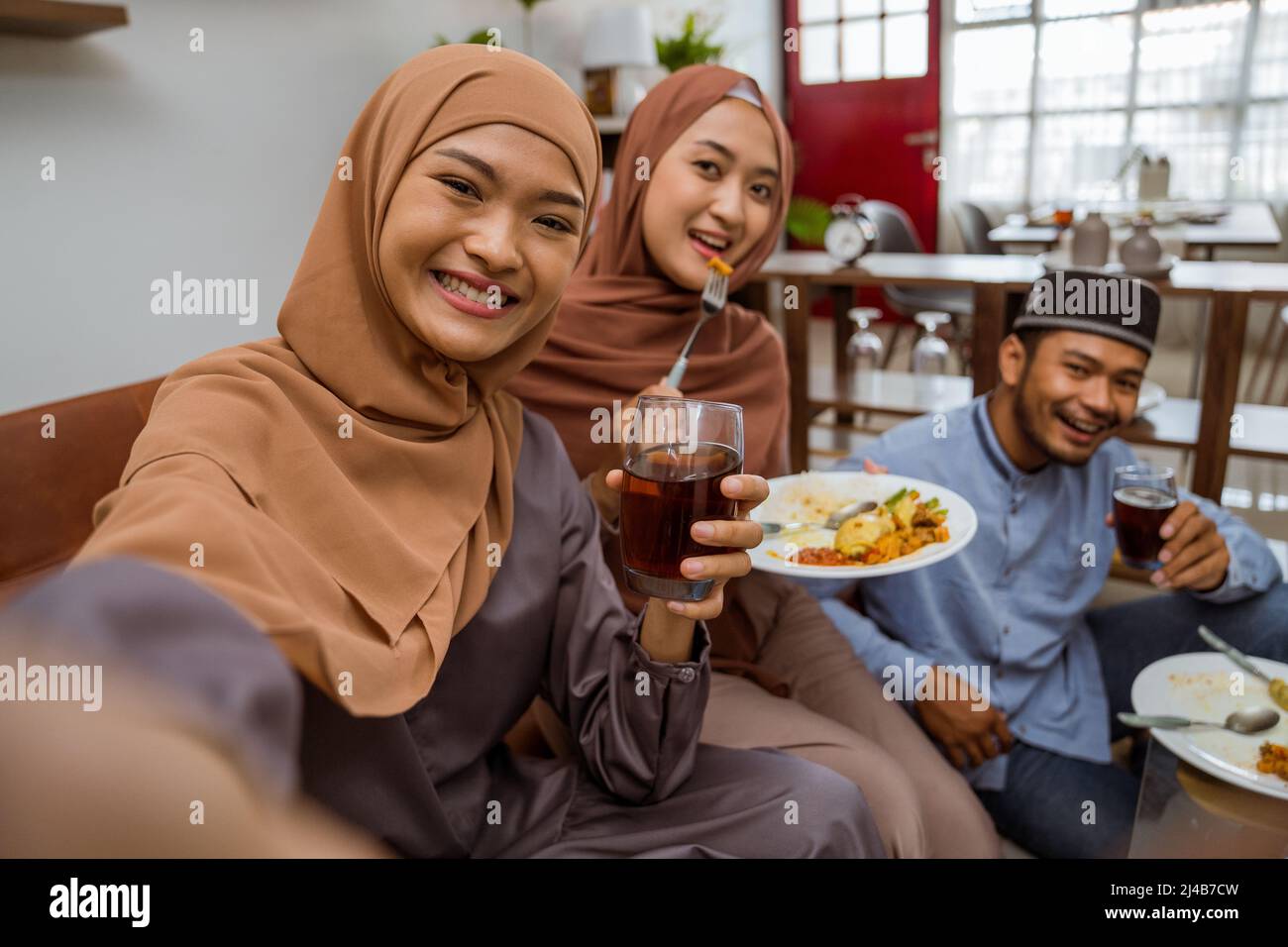 asiatische muslimische Freund machen Selfie zusammen mit Smartphone, während iftar Abendessen Stockfoto