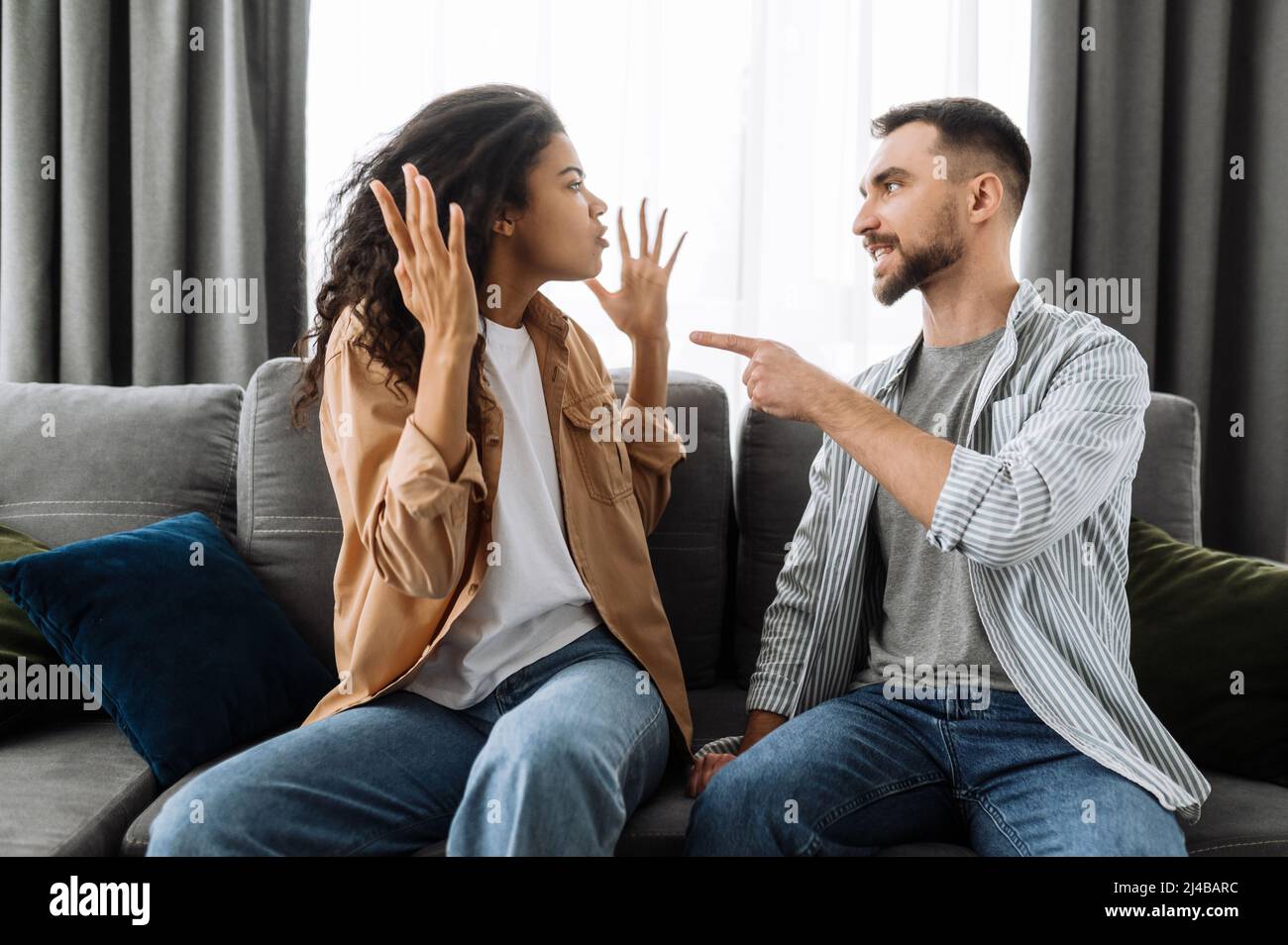 Verheiratete junge Paar emotionale diskutieren über etwas, sie haben Problem. afroamerikanische Frau und kaukasischer Mann sind sich nicht einig haben ein Missverständnis, kann nicht entscheiden, ein Streit Stockfoto