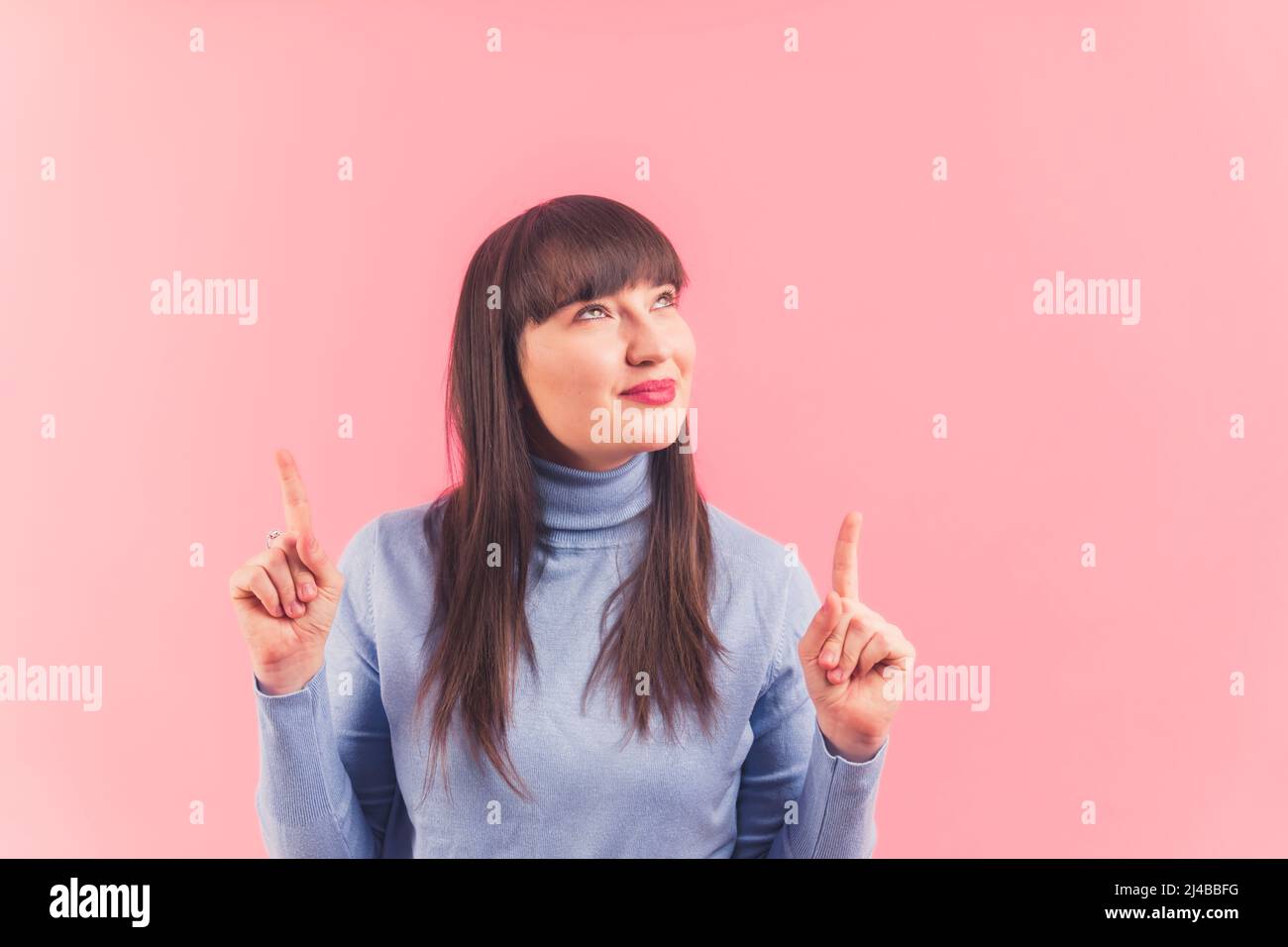 Hübsche junge Frau zeigt und sieht oben, Studio geschossen rosa Hintergrund isoliert Kopie Raum Anzeigen und Promotion-Konzept . Hochwertige Fotos Stockfoto