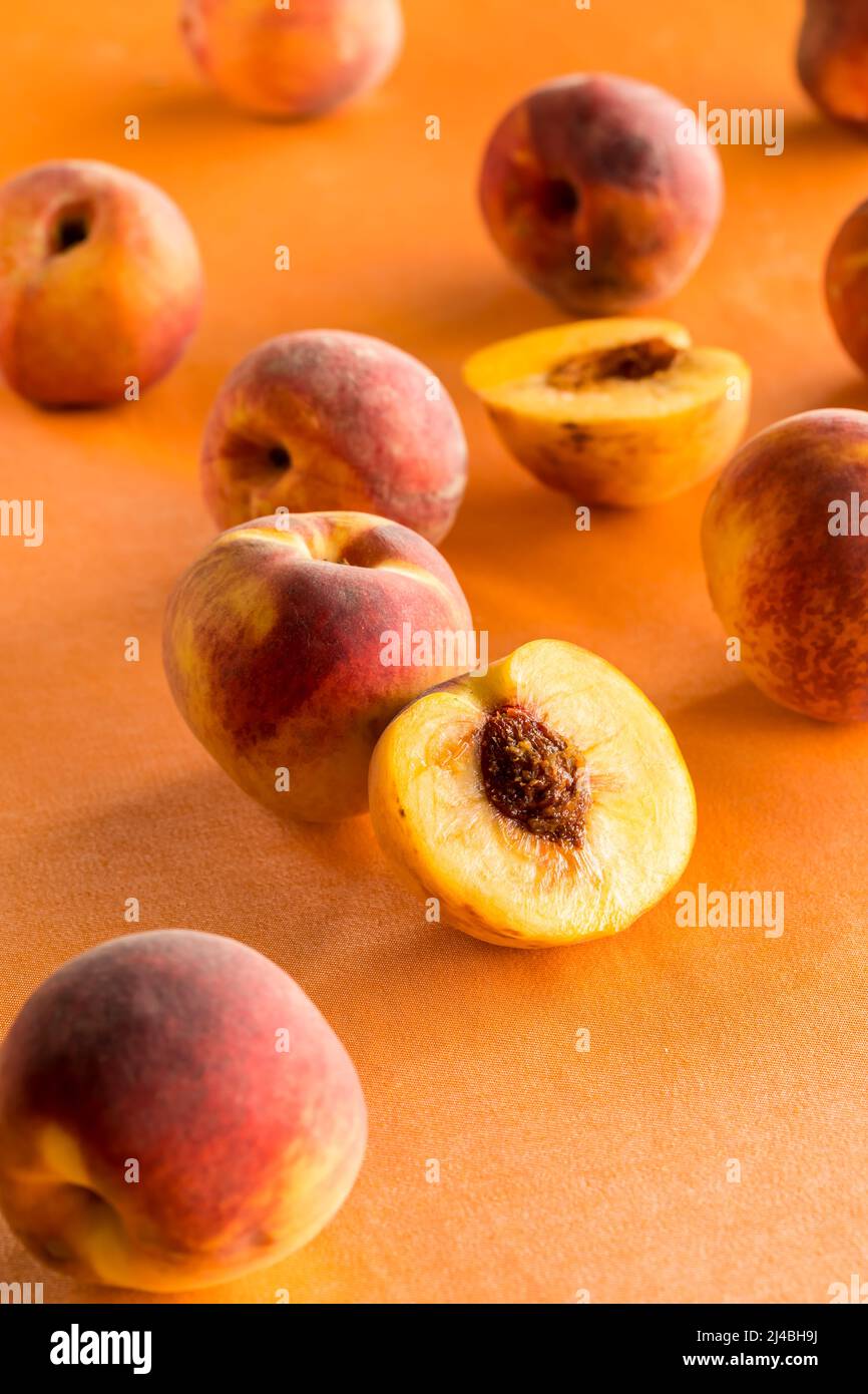 Pfirsiche vor einem hellen Pfirsich Hintergrund verstreut. Stockfoto