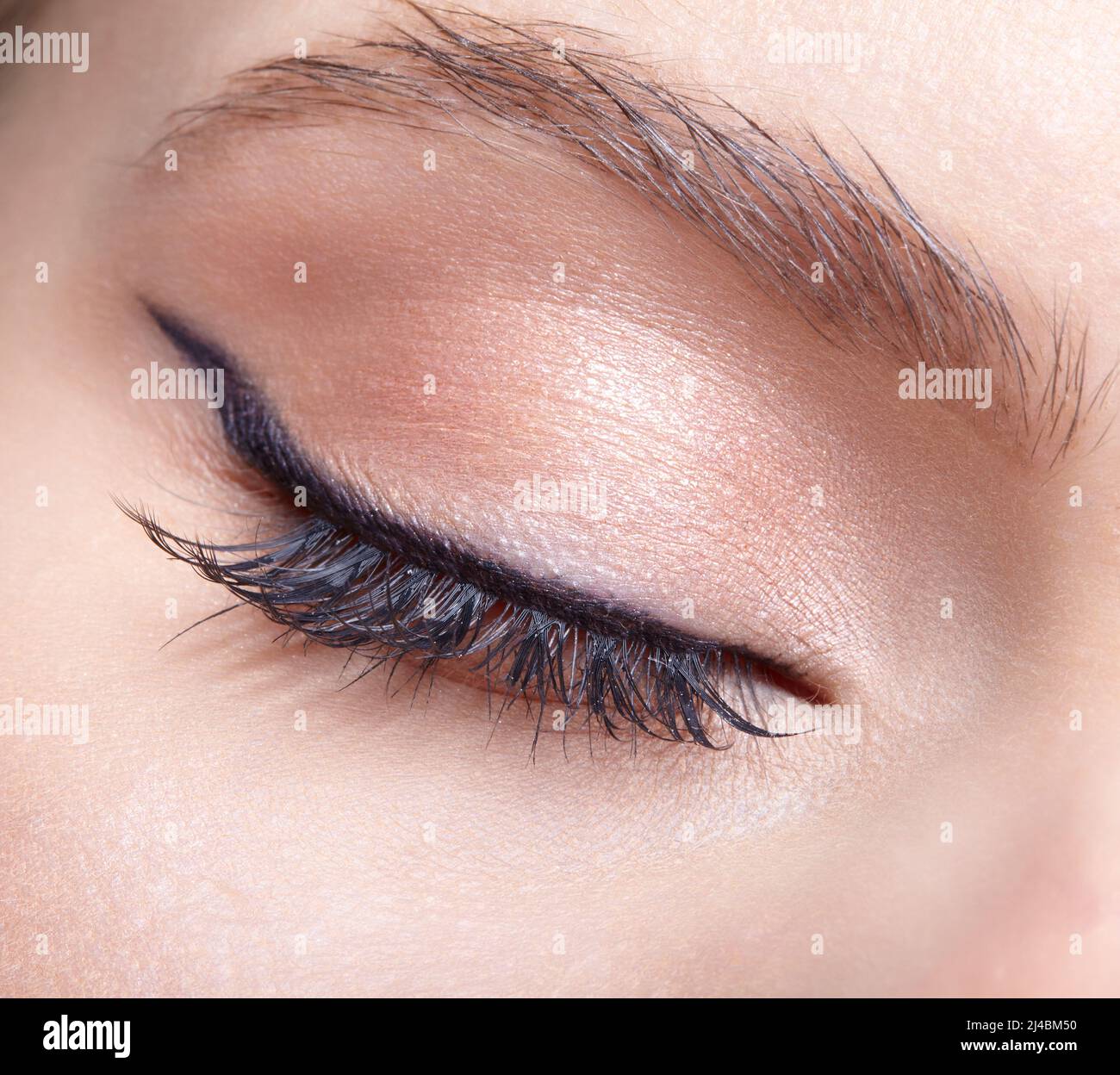 Nahaufnahme einer Makroaufnahme eines weiblichen geschlossenen Auges. Frau mit natürlichen Mode Gesicht Schönheit Make-up. Mädchen mit perfekter Haut und hellrosa Augen Schatten. Stockfoto
