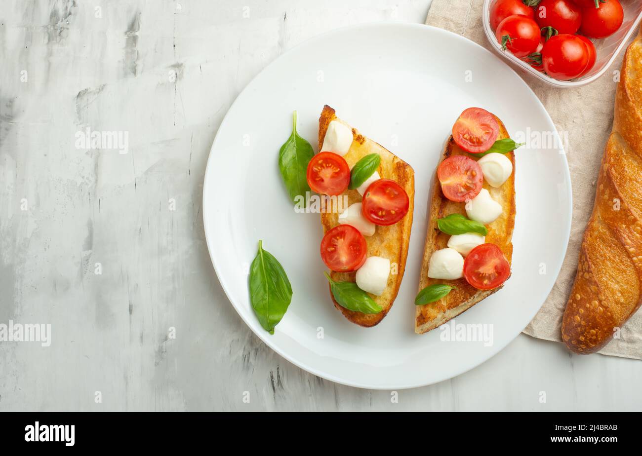Bruschetta mit Tomaten, Mozzarella-Käse und Basilikum auf einem weißen ...