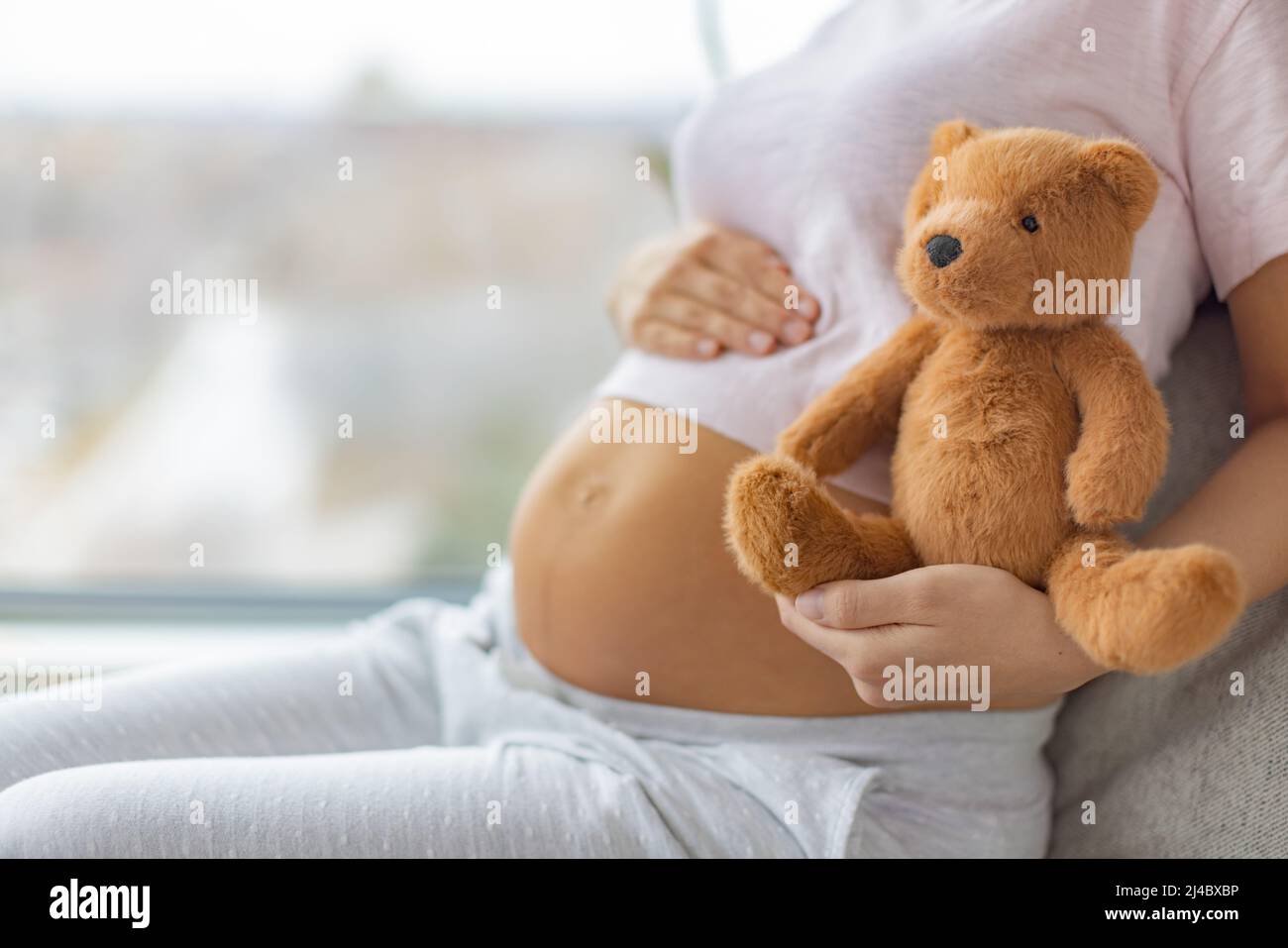 Ich erwarte ein Baby. Eine Schwangerin umarmt den Magen und wartet glücklich auf die Geburt eines Kindes. Familienplanung. Natürliche Schwangerschaft zu Hause Stockfoto