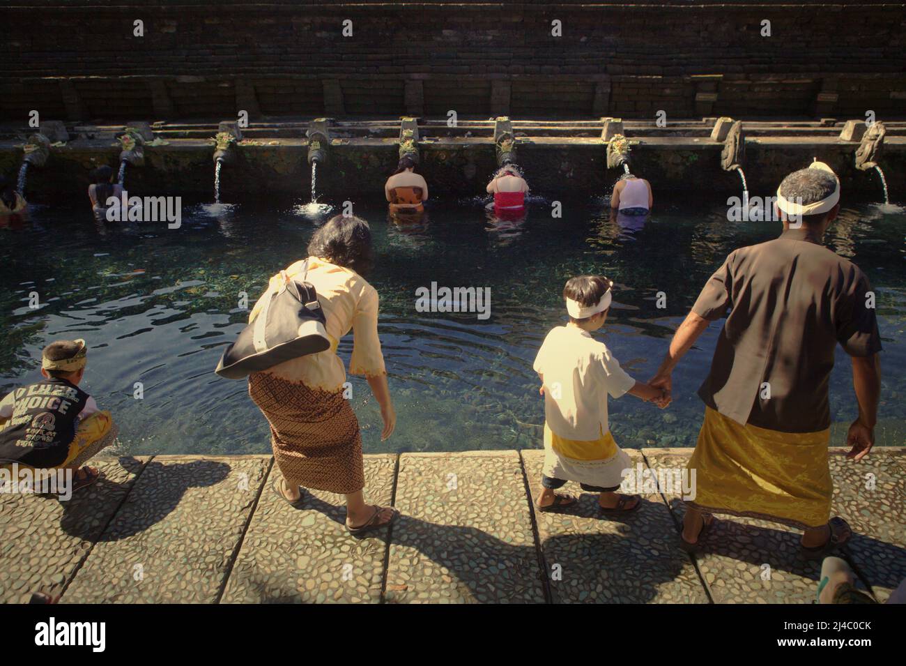 Eine balinesische Familie, die den Swimmingpool des Tirta Empul-Tempels in Templaksiring, Gianyar, Bali, Indonesien besucht. Stockfoto
