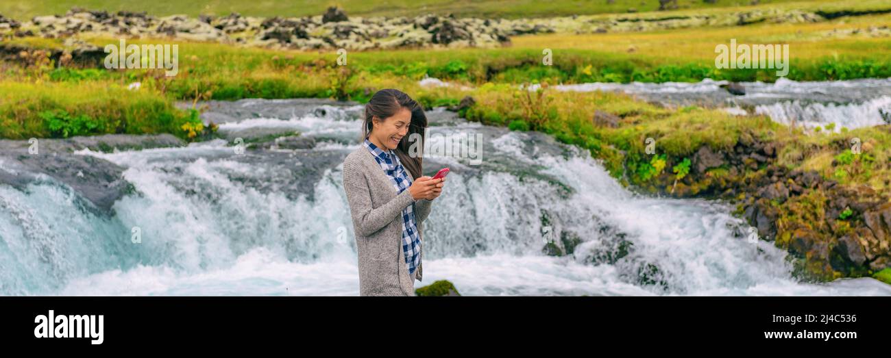 Telefon-App. Frau mit Smartphone in Island Natur. Touristenspaziergängen im Freien mit Smartphone beim Wasserfall auf Island. Mädchen Tourist in lässig Stockfoto