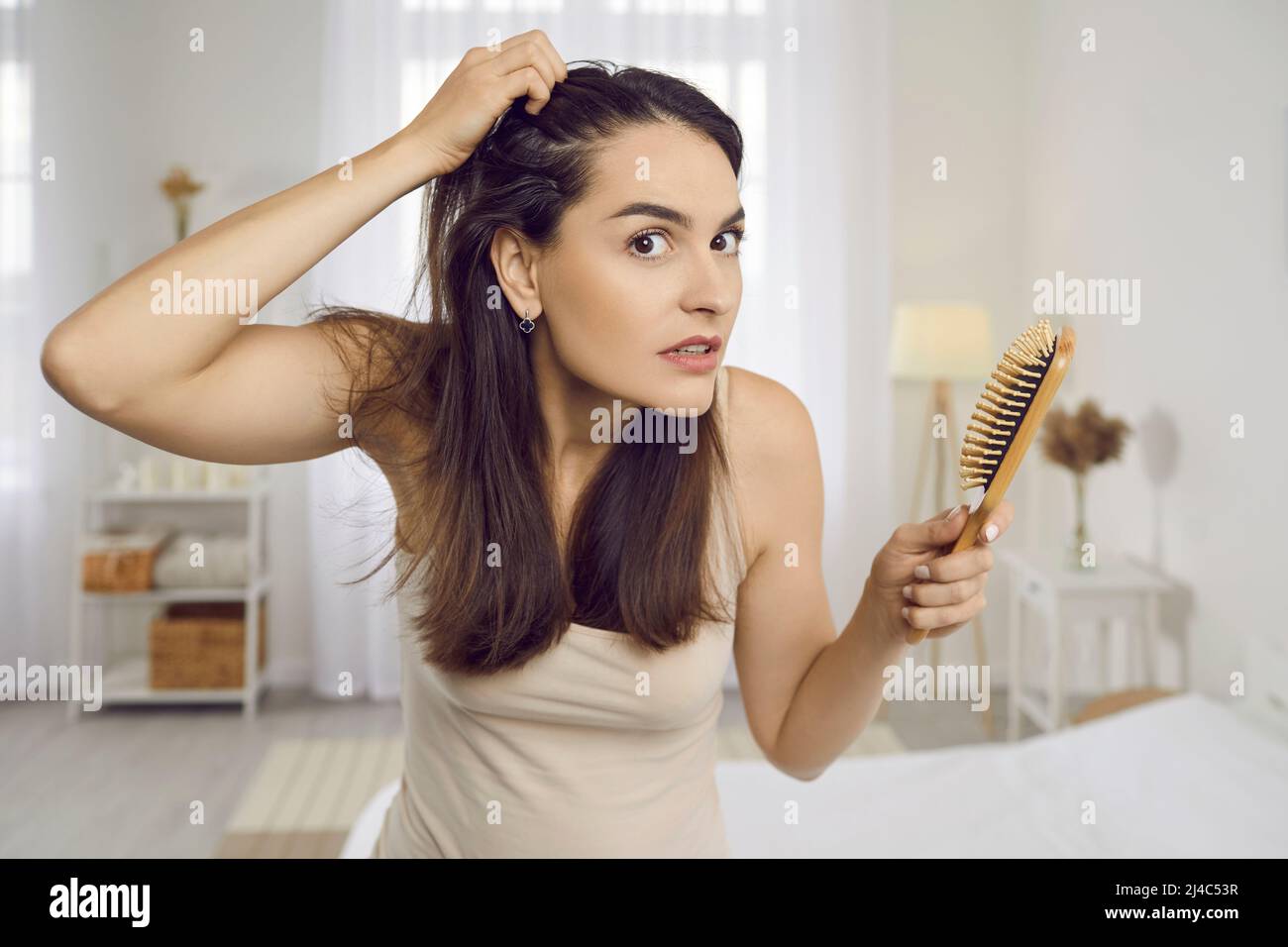 Junge Frau ist durch Anzeichen von Haarausfall Angst oder gestresst wegen der Kopfhautschuppen Stockfoto