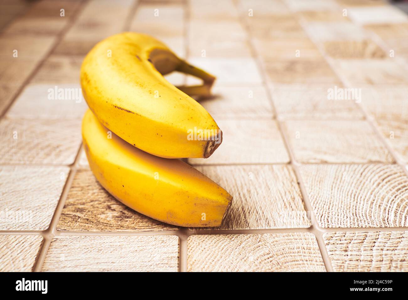Zwei reife Bananen auf einer karierten Holzoberfläche Stockfoto