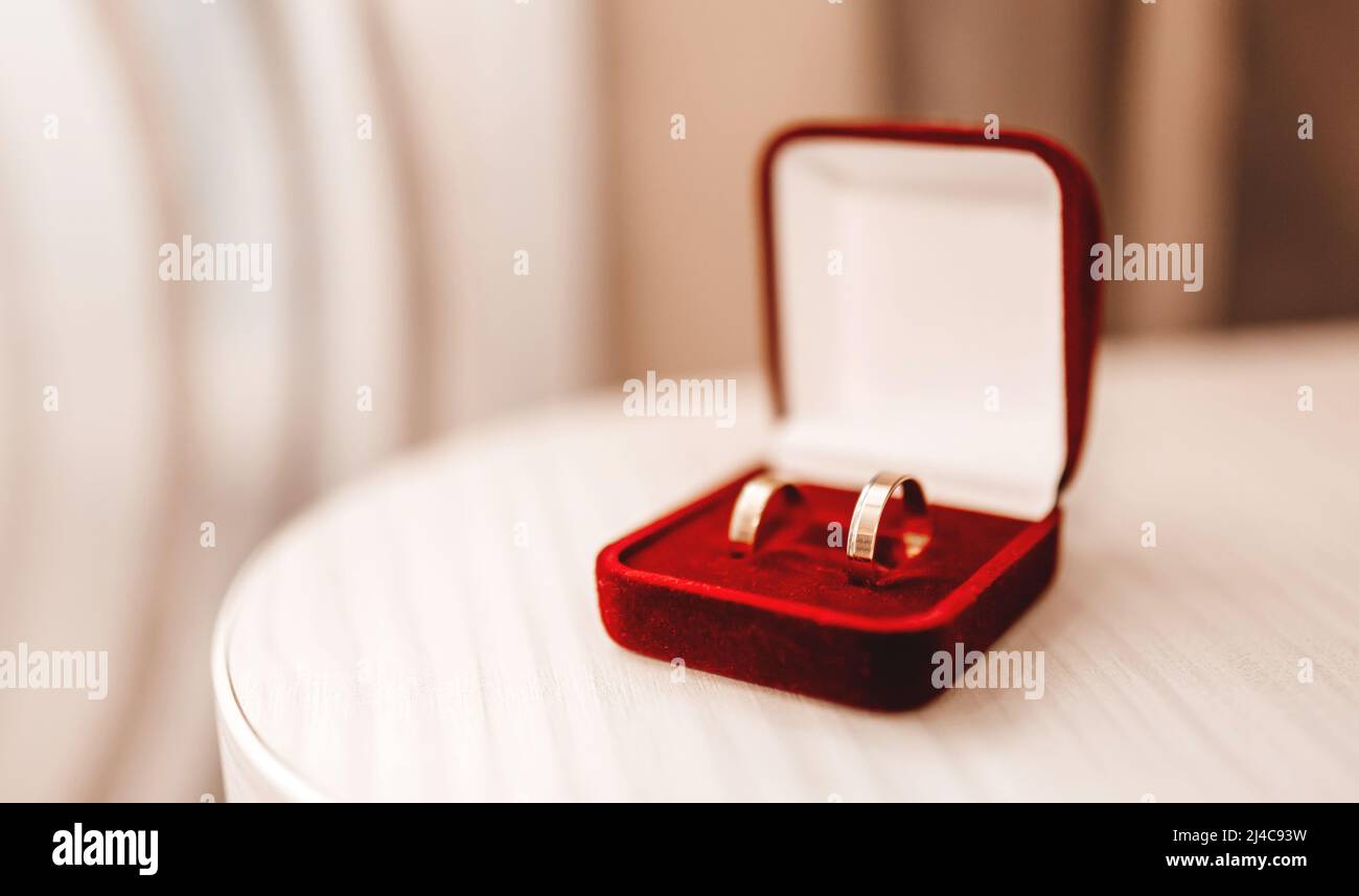 Hochzeitsringe aus Gold in roter Samtbox auf dem Tisch Stockfoto Hochzeitsringe aus Gold in roter Samtbox auf dem Tisch Stockfoto