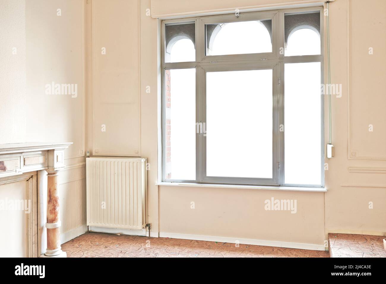 Leere Wohnung mit Fenstern und Marmorkamin vor der Renovierung Stockfoto