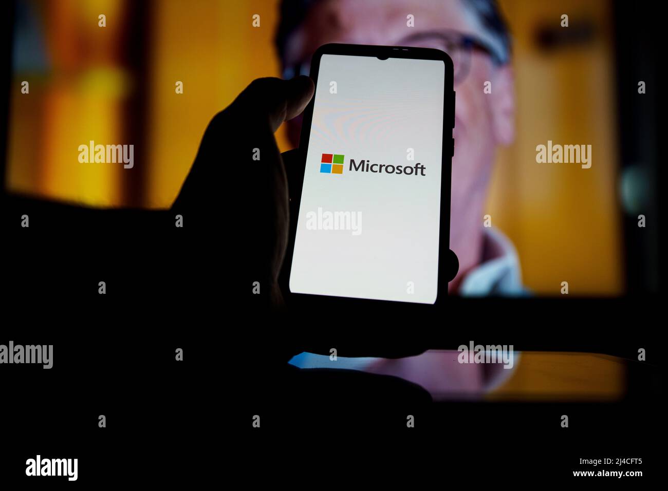 Microsoft-Logo auf dem Bildschirm und Bill Gates im Hintergrund. Er ist Mitbegründer von Microsoft Stockfoto