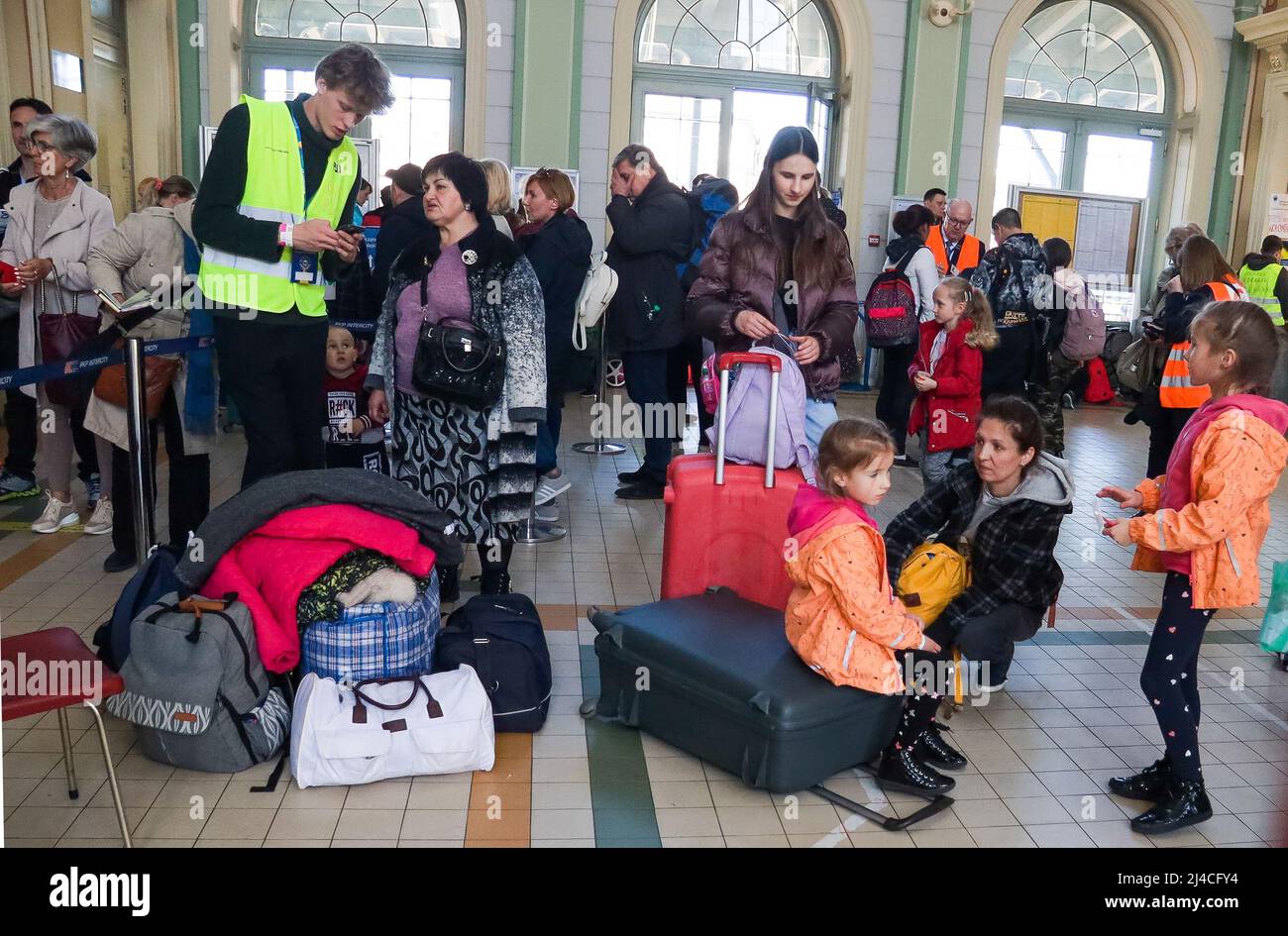 Przemysl, Polen. 13. April 2022. Zwei wunderschöne ukrainische Flüchtlingsschwestern im Alter von 6 und 7 Jahren, die in orange und rosa Kostümen geflossen sind, aus der Ukraine. Sie warten auf einen Zug nach Warschau mit ihrer Mutter, wo sie Zuflucht suchen, bis es sicher ist, in ihre Heimat zurückzukehren. Der Bahnhof Przemysl ist voll von vielen anderen, die vor Putins Terror fliehen, die gerade auch über den Grenzübergang Medyka gekommen sind. (Bild: © Amy Katz/ZUMA Press Wire) Bild: ZUMA Press, Inc./Alamy Live News Stockfoto