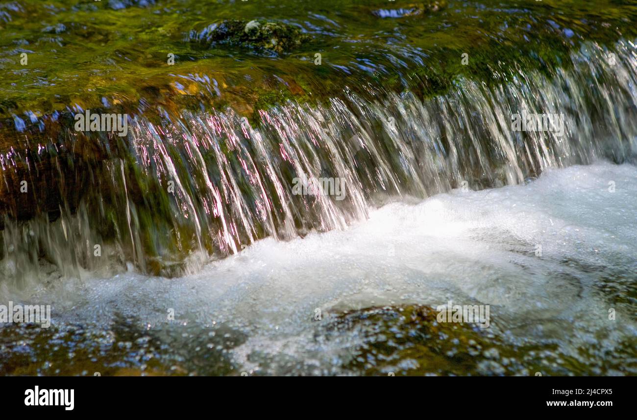 Fließendes Wasser mit kleinem Wasserfall und Lichtreflexen, Bergbach, Inzell, Bayern, Deutschland Stockfoto