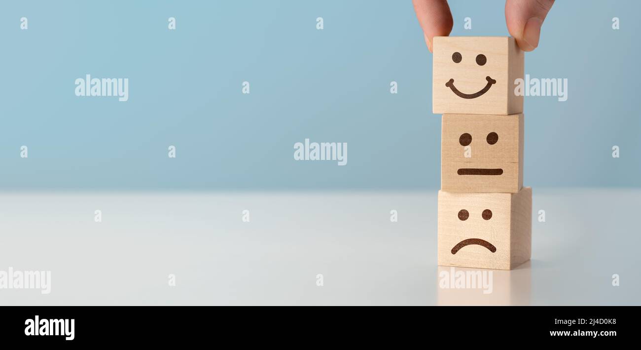 Customer Service Bewertung und Zufriedenheit Umfrage Konzepte. Kunden Hand gepflückt glückliches Gesicht Lächeln Gesicht Symbol auf Holzklötzen, blauer Hintergrund. cop Stockfoto