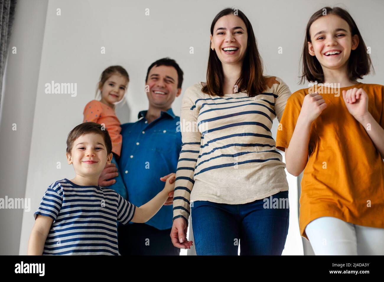 Aufgeregte Kinder, die mit ihren Eltern nach Hause kommen. Kinder nach Hause mit Eltern Mama und Papa, lächelnd niedlichen Kinder Bruder und Schwestern, Eingabe ein Stockfoto