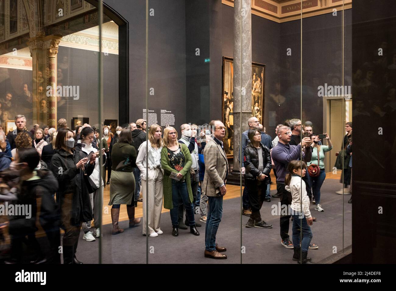 Im Rijksmuseum in Amsterdam, Niederlande, bewundern die Menschen die Nachtwache von Rembrandt hinter ihrem Schutzglas. Stockfoto
