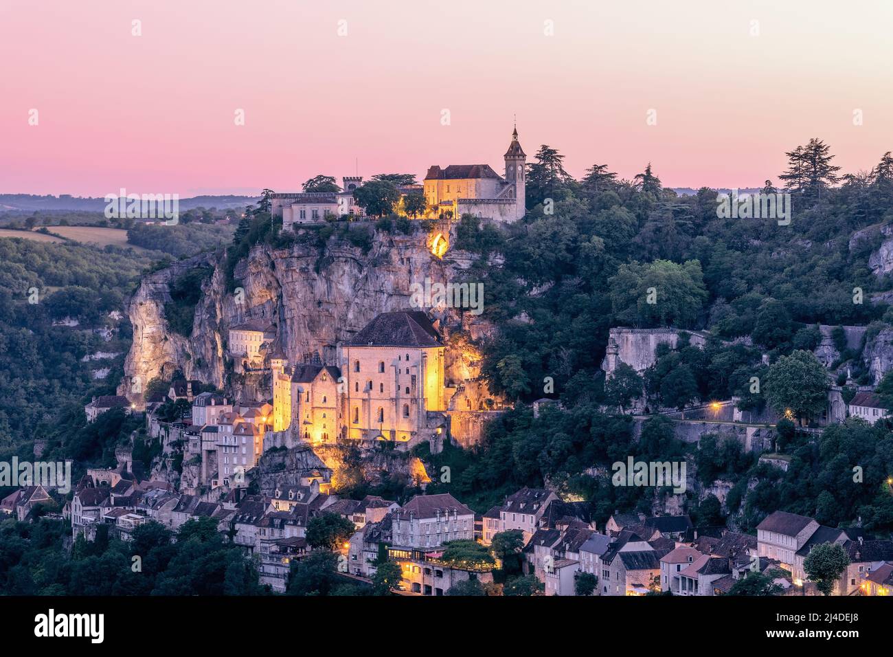 Während der Sommerdämmerung beginnen die ersten Scheinwerfer die wichtigsten religiösen Stätten der fabelhaften Stadt Rocamadour zu beleuchten. Lot, Okzitanien, Frankreich Stockfoto