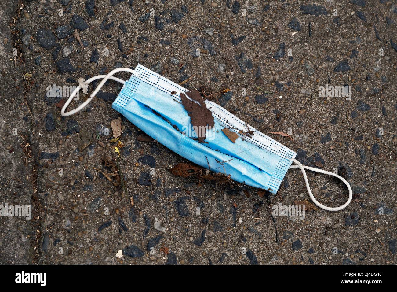 Medizinische Gesichtsmaske auf dem Boden auf der Straße. Gebrauchte Gesichtsmaske nicht ordnungsgemäß entsorgen. Stockfoto