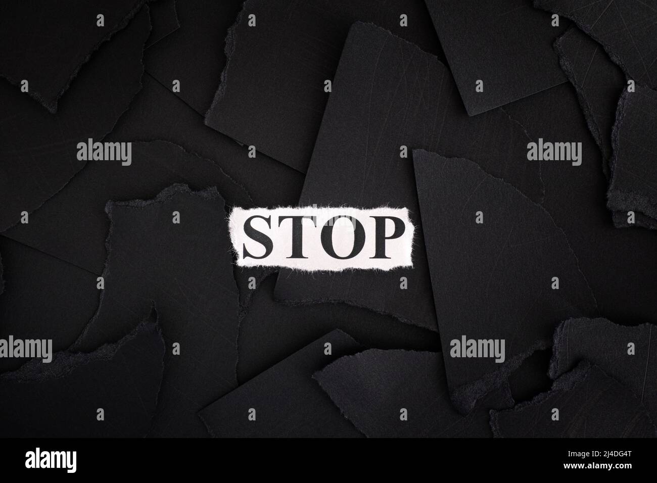 Zerrissene schwarze Papierstücke mit dem Wort Stop. Konzeptbild. Nahaufnahme. Stockfoto