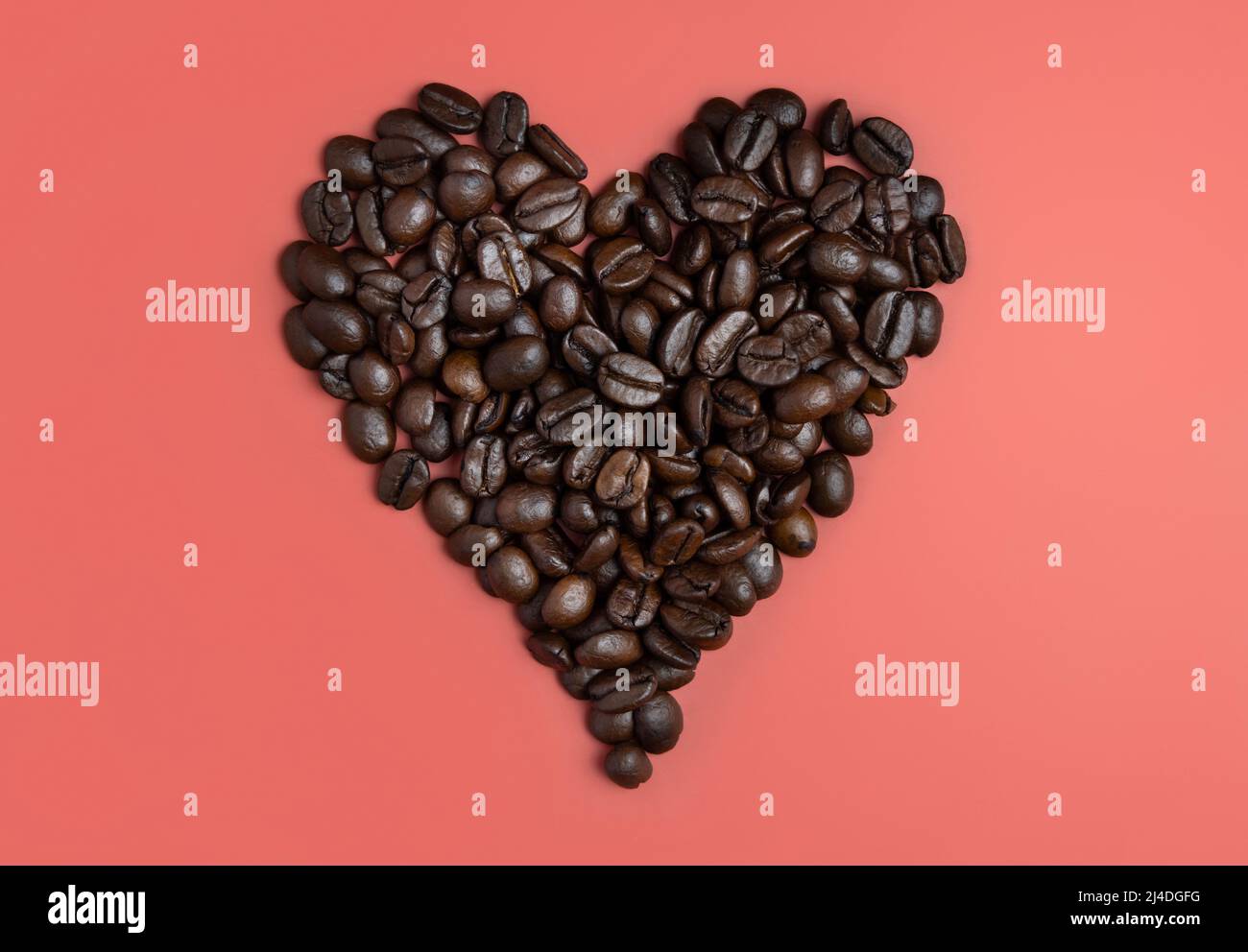 Herz aus gerösteten Kaffeebohnen Draufsicht auf rosa Hintergrund. Repräsentieren Frühstück, Liebe, Energie, Frische oder Aroma Stockfoto