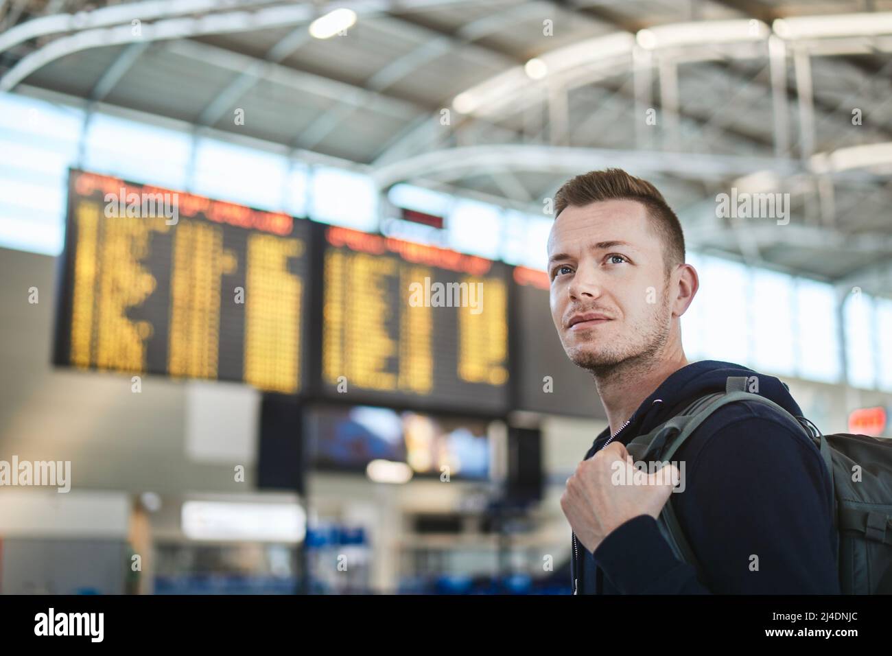 Mann mit Rucksack am Flughafen. Porträt des Touristen gegen Ankunft und Abreise Bord. Stockfoto